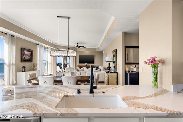 kitchen featuring crown molding, sink, pendant lighting, and ceiling fan with notable chandelier