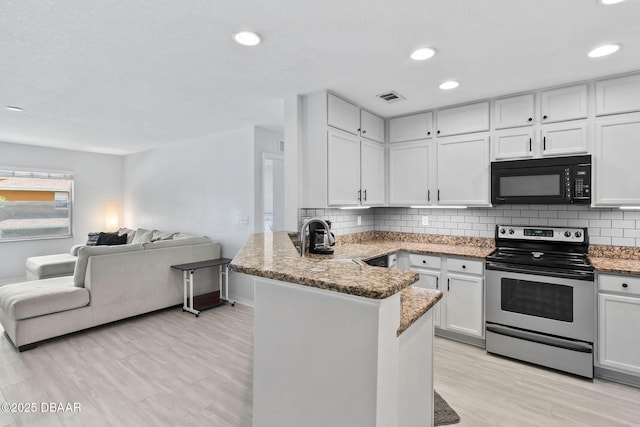 4600 E Moody Blvd Unit 14-O, Bunnell, FL 32110 - kitchen featuring electric stove, black microwave, open floor plan, a peninsula, and white cabinets