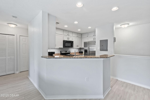 4600 E Moody Blvd Unit 14-O, Bunnell, FL 32110 - kitchen featuring appliances with stainless steel finishes, electric panel, dark stone countertops, tasteful backsplash, and light wood-type flooring