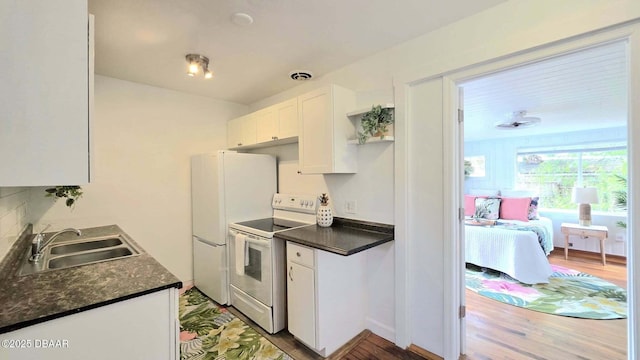 119 Rogers Park Dr, Ormond Beach, FL 32174 - kitchen featuring white appliances, a sink, dark countertops, white cabinetry, and light wood finished floors