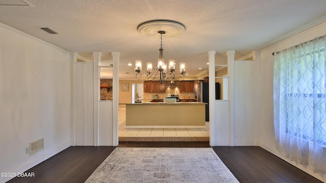 103 Cone Rd, Ormond Beach, FL 32174 - kitchen with a chandelier, dark wood finished floors, brown cabinetry, backsplash, and stainless steel range oven