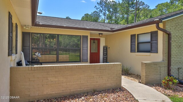 103 Cone Rd, Ormond Beach, FL 32174 - view of exterior entry with stucco siding, brick siding, and roof with shingles