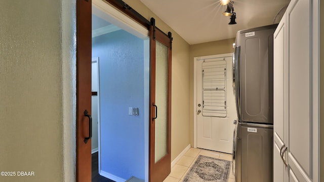 103 Cone Rd, Ormond Beach, FL 32174 - laundry room with stacked washer / drying machine, light tile patterned flooring, a barn door, and baseboards