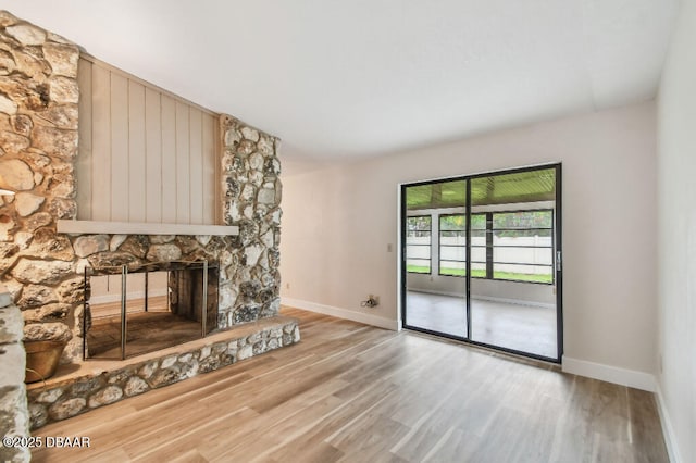 2421 Needle Palm Dr, Edgewater, FL 32141 - unfurnished living room with baseboards, wood finished floors, and a stone fireplace