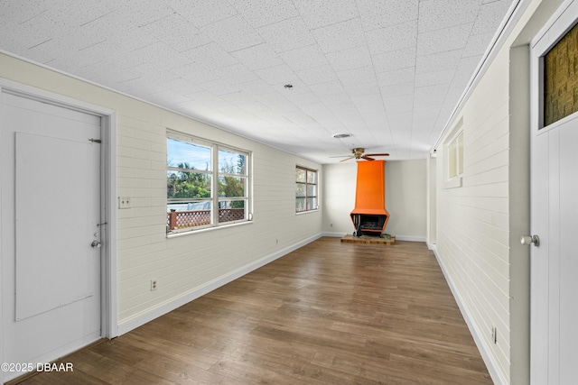 unfurnished living room featuring hardwood / wood-style flooring, a wood stove, and ceiling fan