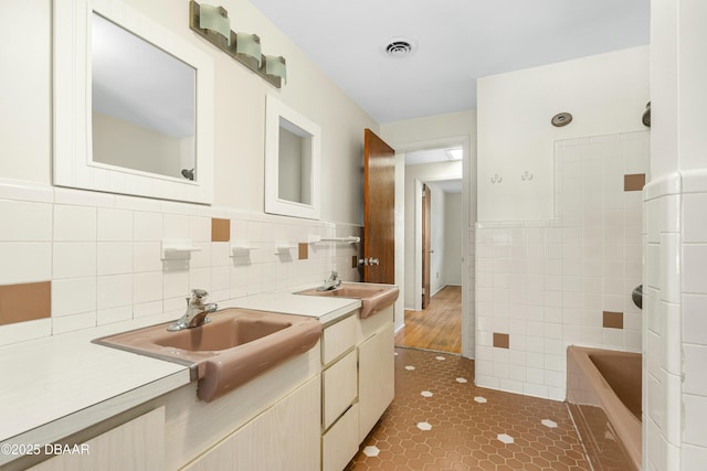 bathroom with tile patterned floors, vanity, a bathing tub, and tile walls