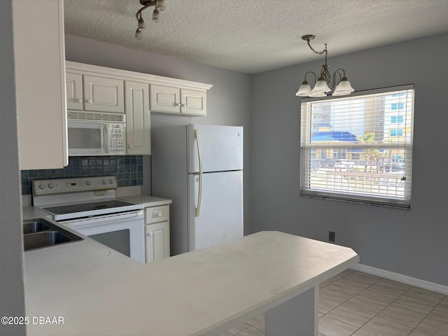 kitchen with sink, an inviting chandelier, pendant lighting, white appliances, and white cabinets