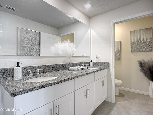 bathroom with vanity, toilet, and a textured ceiling