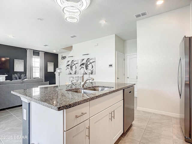 kitchen featuring white cabinets, a center island with sink, sink, dark stone countertops, and stainless steel appliances