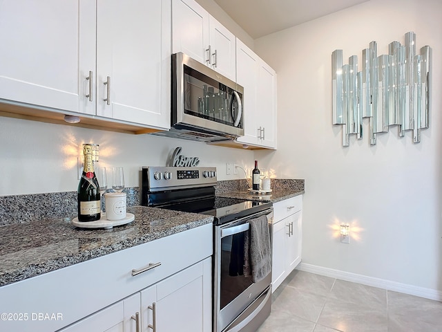 kitchen featuring dark stone countertops, white cabinets, and stainless steel appliances