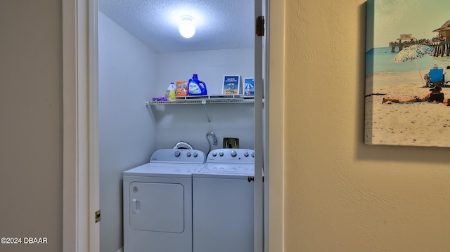 clothes washing area featuring a textured ceiling and washer and dryer