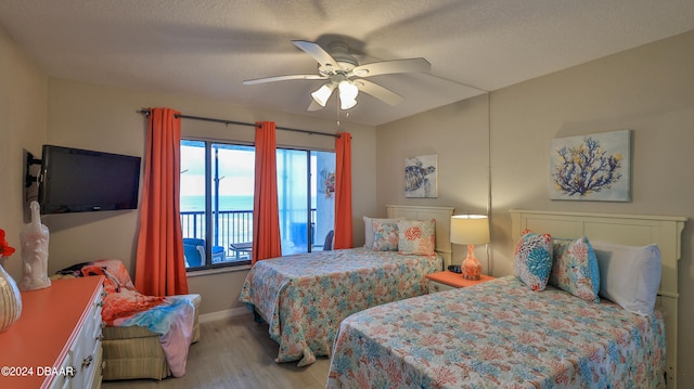 bedroom with a textured ceiling, light wood-type flooring, access to outside, and ceiling fan