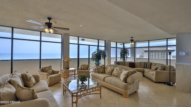 tiled living room featuring a water view, ceiling fan, and plenty of natural light