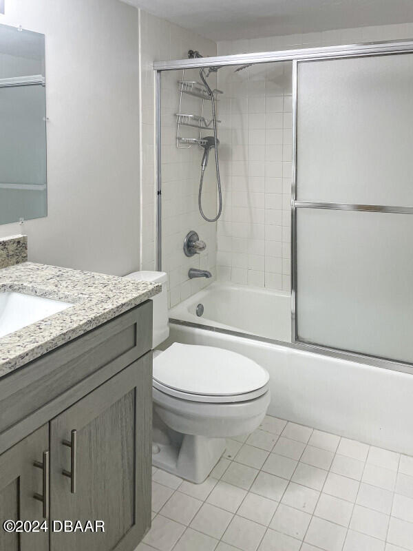 full bathroom featuring enclosed tub / shower combo, tile patterned flooring, vanity, and toilet