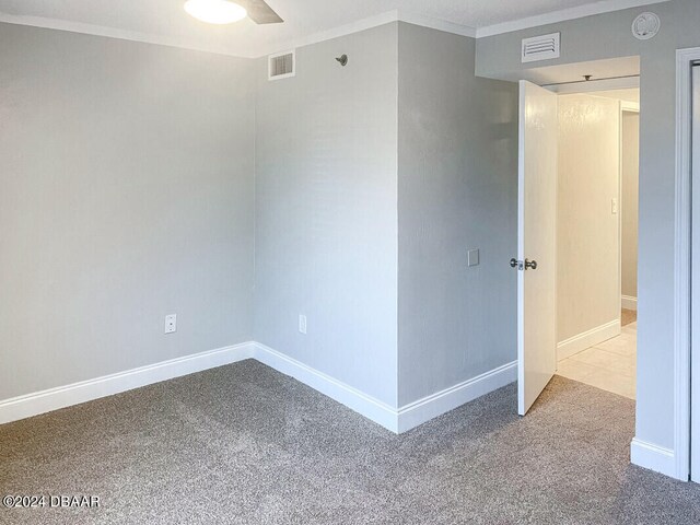 carpeted empty room featuring crown molding