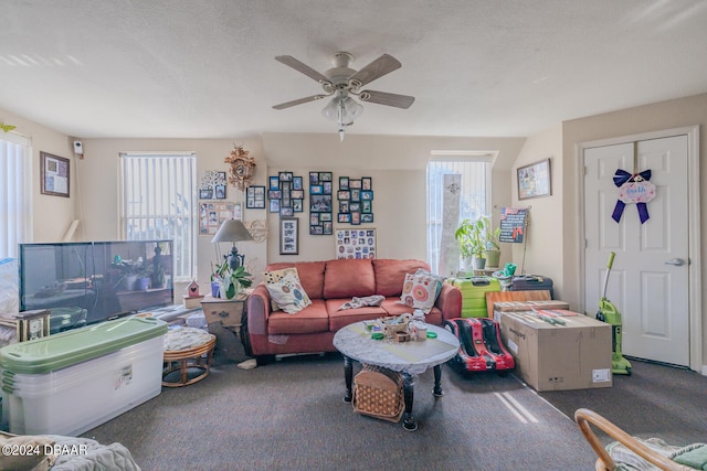 living room featuring a textured ceiling, dark colored carpet, and ceiling fan