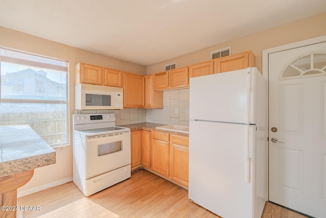 kitchen featuring light brown cabinets, light hardwood / wood-style flooring, tasteful backsplash, and white appliances