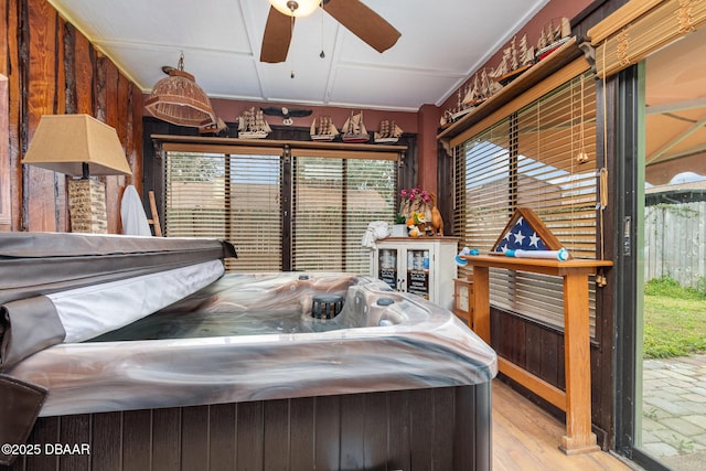 bedroom featuring ceiling fan, light hardwood / wood-style flooring, ornamental molding, and wooden walls