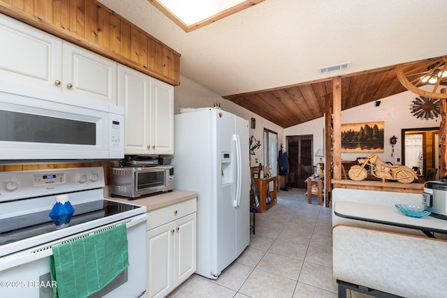 kitchen featuring vaulted ceiling, light tile patterned floors, white cabinets, and white appliances