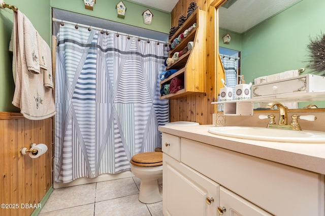 bathroom with toilet, vanity, tile patterned floors, and wooden walls