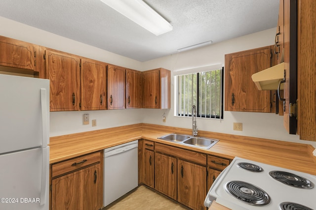 kitchen with range hood, white appliances, sink, and a textured ceiling