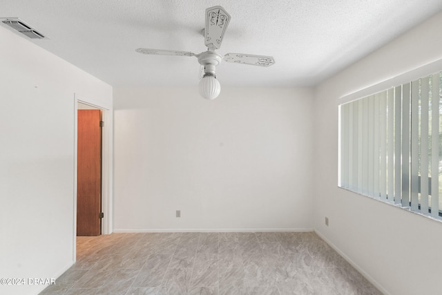 unfurnished room with ceiling fan and a textured ceiling