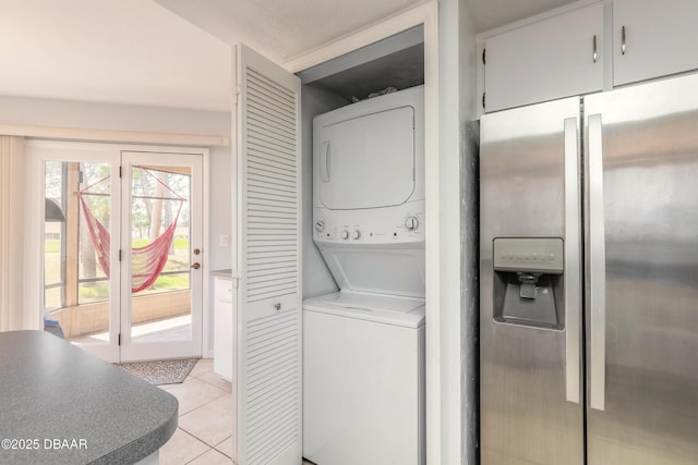 washroom with stacked washing maching and dryer, laundry area, and light tile patterned floors