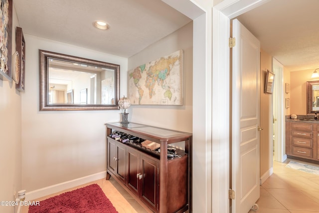 corridor featuring recessed lighting, baseboards, a sink, and light tile patterned floors