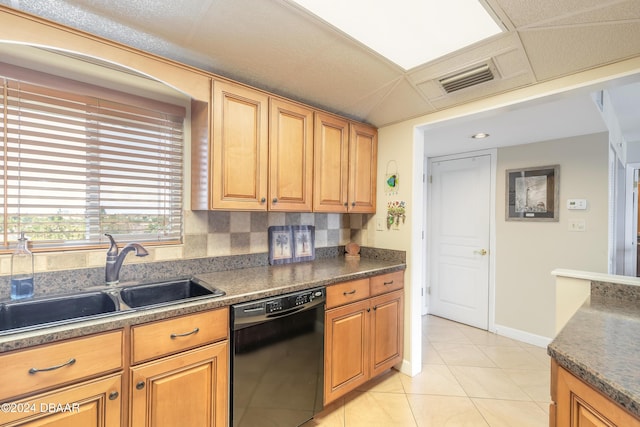 kitchen with dark countertops, a sink, light tile patterned floors, baseboards, and black dishwasher
