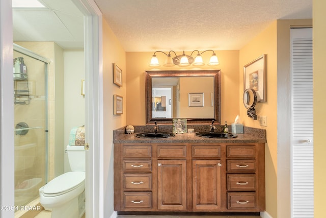 bathroom featuring a sink, a stall shower, toilet, and double vanity