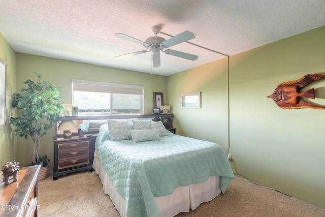 bedroom with a textured ceiling, ceiling fan, and light carpet