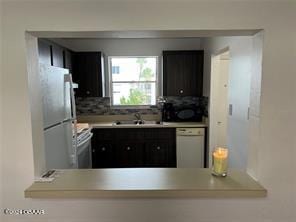 kitchen with white appliances, sink, and backsplash