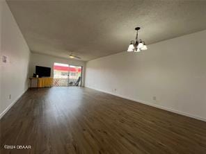 unfurnished living room with an inviting chandelier and dark hardwood / wood-style flooring