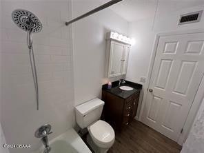 full bathroom with vanity, tiled shower / bath, toilet, and wood-type flooring