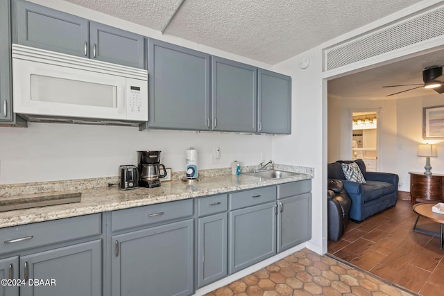 kitchen with ceiling fan, sink, and a textured ceiling