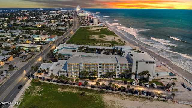 aerial view at dusk featuring a beach view and a water view