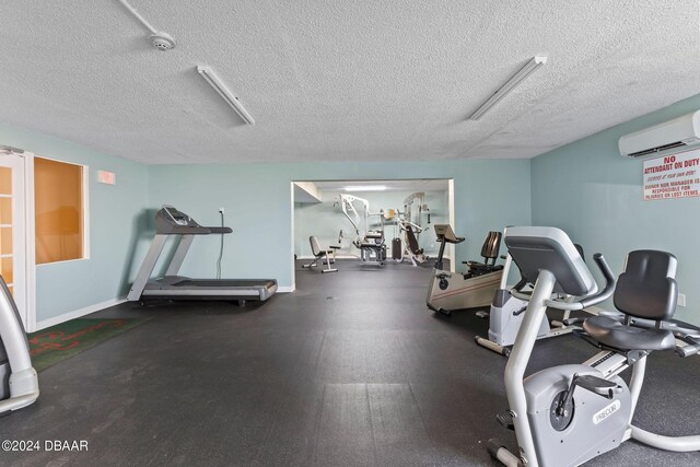 exercise room featuring a wall mounted air conditioner and a textured ceiling