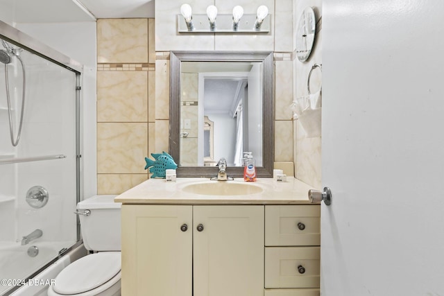 full bathroom featuring toilet, vanity, tile walls, and combined bath / shower with glass door