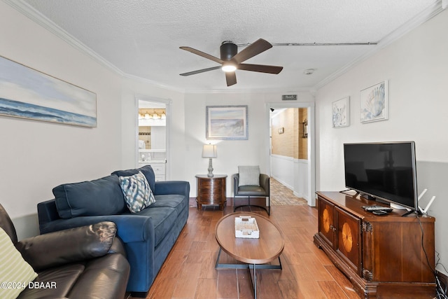 living room featuring a textured ceiling, ceiling fan, and crown molding