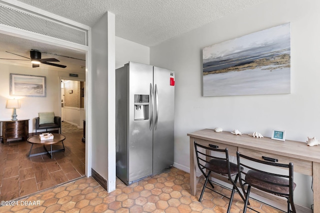 kitchen with ceiling fan, stainless steel fridge, a textured ceiling, and wooden counters