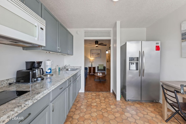 kitchen featuring stainless steel fridge, a textured ceiling, ceiling fan, and sink