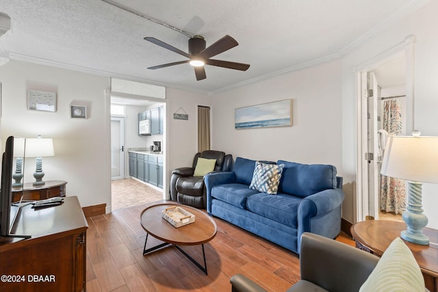 living room with a textured ceiling, ceiling fan, and ornamental molding