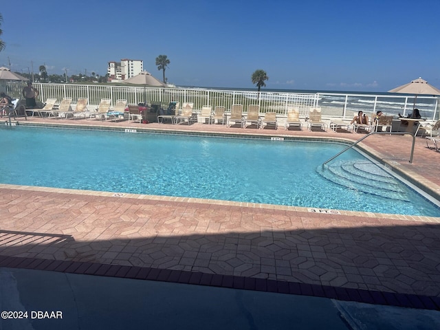 view of swimming pool with a patio area and a water view