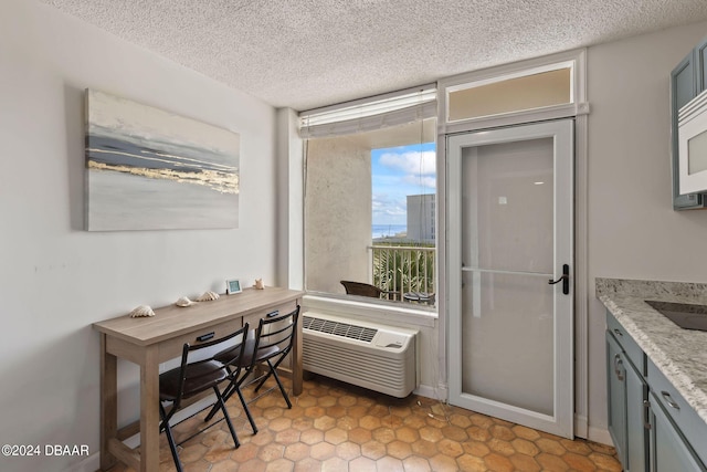 doorway to outside featuring a wall mounted air conditioner and a textured ceiling