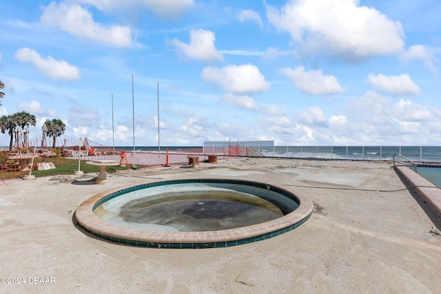 view of pool with a water view and an in ground hot tub