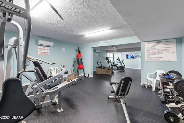 exercise room with a textured ceiling and a wall mounted AC