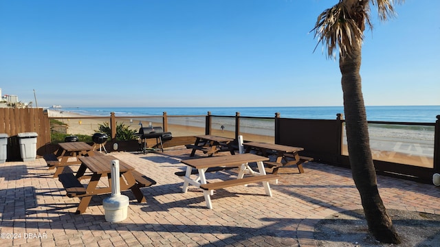 view of patio featuring a water view, a beach view, and a grill