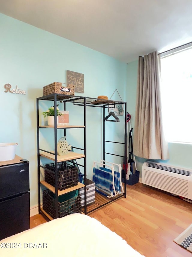 bedroom featuring hardwood / wood-style flooring and a wall mounted AC