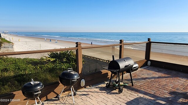 view of patio / terrace with a water view, a beach view, and a grill