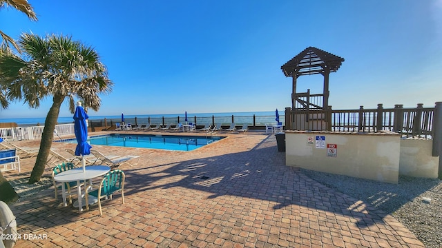 view of pool with a water view and a patio